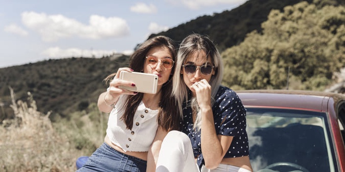 Young women sitting on car posing for self portrait
